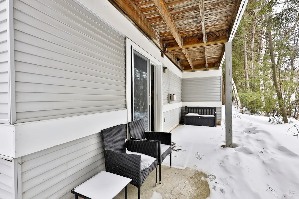 A tranquil view of the front porch with outdoor seating, surrounded by freshly fallen snow. The peaceful setting highlights the opportunity to relax outdoors and enjoy the crisp mountain air, even in winter.