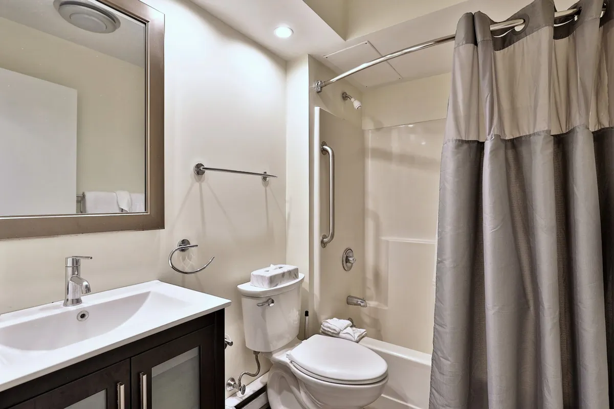 A well-appointed bathroom with a vanity sink, a mirror, a spacious shower, and a toilet. The mood is calm and inviting, suggesting a refreshing space for morning or evening routines.